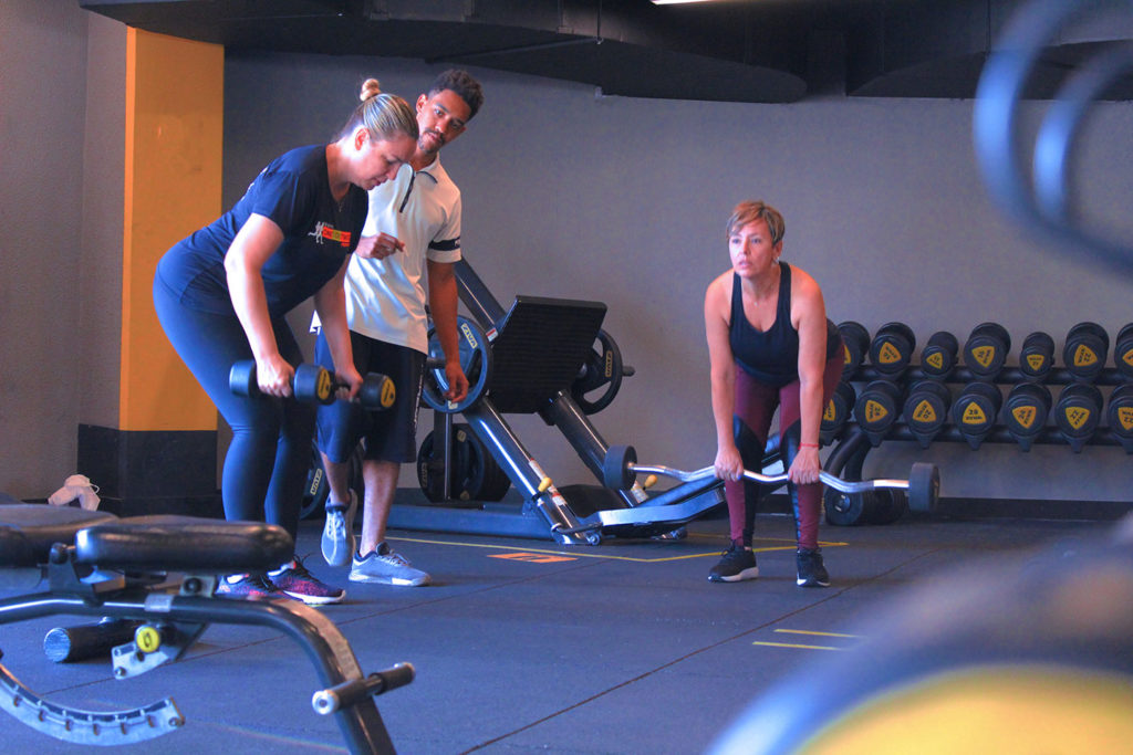 Alunas treinando enquanto personal trainer orienta